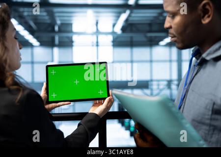 Team of admins in data center using green screen tablet, refining server virtualization strategies. Server room IT specialists doing brainstorming, using chroma key device to configure cluster nodes Stock Photo