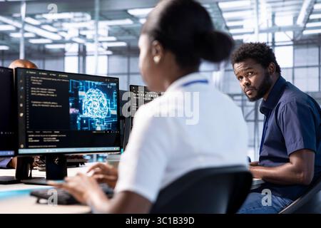 Teamworking admins in artificial intelligence server farm checking recovery plan, monitoring energy consumption. Machine learning experts in data center making sure rigs are functioning optimally Stock Photo