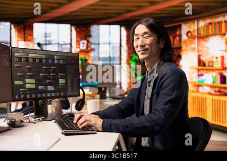 Portrait of smiling startup manager leveraging machine learning technology in office to gain competitive edge. Happy Asian Silicon Valley company IT expert working on rapid technological advancement Stock Photo