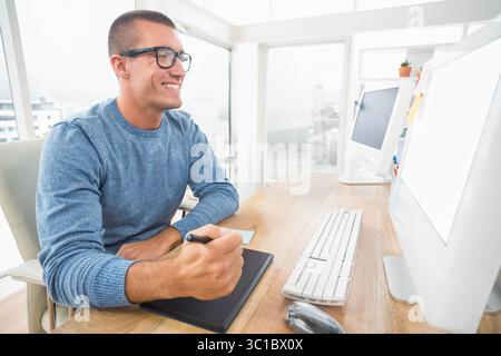 Graphics tablet resting beside keyboard and mouse on desk in modern office near city windows Stock Photo
