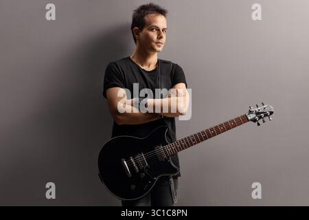 Young man with an electric guitar leaning on a wall Stock Photo