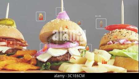Displaying three mini burgers on wooden board with sweet potato fries in studio, with data icons Stock Photo