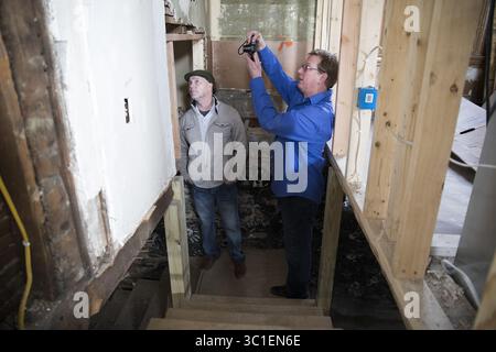 February 23, 2017 - Minneapolis, MN, U.S.A - Matt Zinser, right, of Load-Bearing, Inc, who is acting as a liaison between the general contractors and Hennepin County, with John Donohue of Hennepin County, takes some photos of the work being done on a home on James Avenue North in Minneapolis. ....BACKGROUND INFORMATION: Tour of homes under renovation in north Minneapolis on Thursday, February 23, 2017. A new Hennepin County pilot program is partnering with small contractor businesses to renovate tax forfeited homes. (Credit Image: Leila Navidi/Minneapolis Star Tribune/TNS via ZUMA Wire) Stock Photo