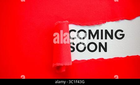 Coming Soon Message Revealed Under Torn Red Paper on White Background Stock Photo