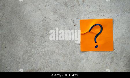 Blue Question Mark on an Orange Sticky Note on a Cracked Concrete Background Stock Photo