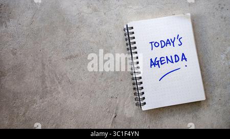 Today's Agenda Hand-Written in a Dot-Grid Notebook on a Cracked Concrete Background Stock Photo