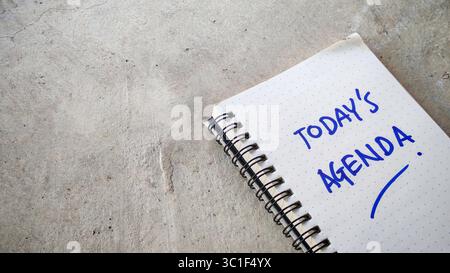 Today's Agenda Hand-Written in a Dot-Grid Notebook on a Cracked Concrete Background Stock Photo