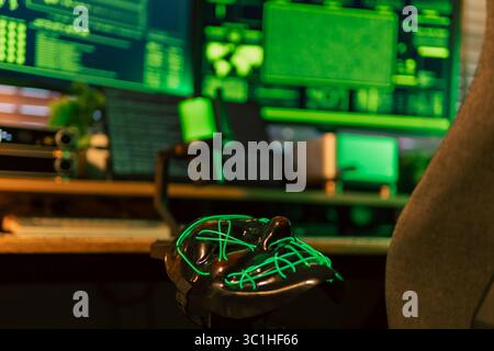 Neon-green hacker mask rests center stage on a cyber desk, while three widescreen monitors overflow with rapidly scrolling code. Stock Photo