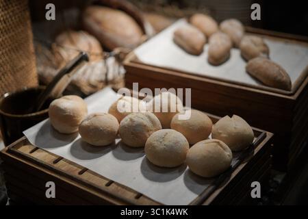Freshly baked bread rolls on parchment paper in wooden trays. Warm, rustic bakery or breakfast buffet concept. Close up with soft focus background. Stock Photo