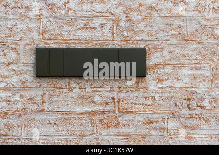 Modern dark grey light switch panel on a rustic whitewashed brick wall. Concept of home renovation, interior design, and smart home technology. Stock Photo