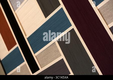 Geometric color block pattern made from wrapped thread or yarn. Abstract background with textile art in green, pink, brown, and black colors. Stock Photo