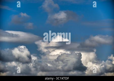 Dramatic clouds against a clear blue sky create a stunning natural display, showcasing various shapes and textures. Stock Photo