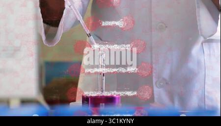 Scientist wearing lab coat, gloves dispensing liquid with pipette into purple test tube rack in lab Stock Photo