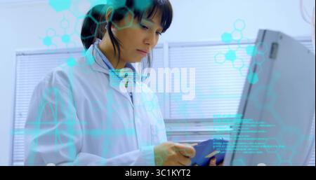 Woman in lab coat analyzing data on monitor at research lab, with clipboard and molecular overlays Stock Photo