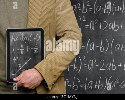 Teacher holding a Tablet Computer in front of a chalkboard Stock Photo