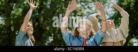 Children Laughing and Playing Outdoors with Bubbles in Park Stock Photo