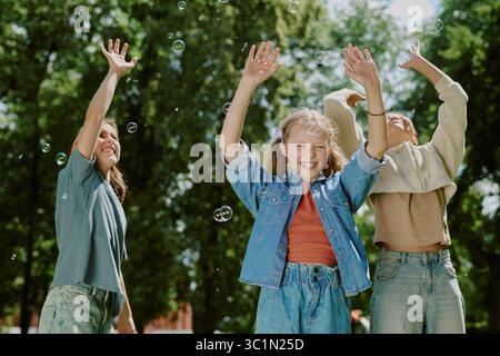 Group of Diverse Children Laughing and Playing with Bubbles in Park Outdoors Stock Photo