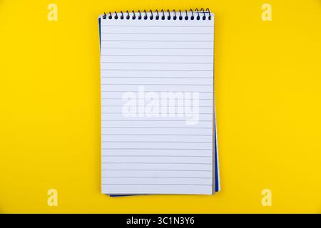 blank Spiral bound notebook with lined pages on vibrant yellow background for note-taking and sketching applications Stock Photo