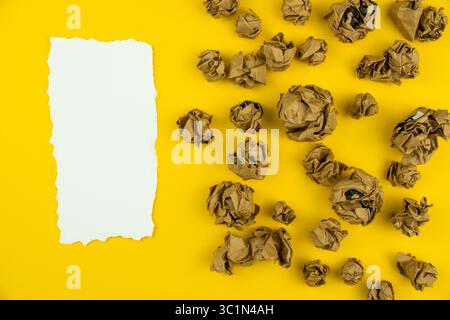 crumpled brown paper balls around a white torn paper sheet in center, ideas, brainstorm and thinking concept Stock Photo
