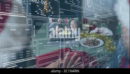 Manipulating gloved Santa hand touching holographic charts on family call at home desk with cookies Stock Photo