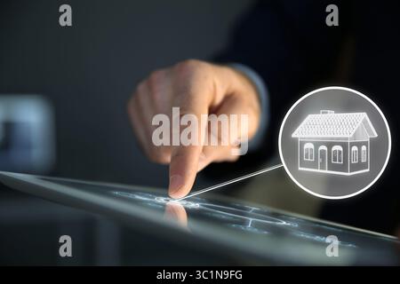 Real estate agent using tablet computer, closeup. House icon on virtual screen Stock Photo