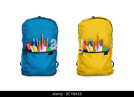 Two children's school backpacks, bags, stuffed with pens and pencils for going back to school to study and learn in blue and yellow white background. Stock Photo