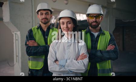 Confident glad Caucasian workers males architects builders men team coworkers controller woman crossing arms cooperation inspector looking at camera Stock Photo