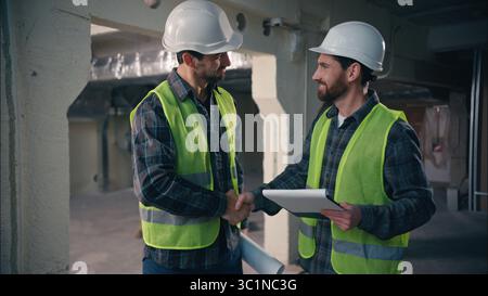 Glad Caucasian workers men guys holding draft papers mechanics working project architects plan build manufacture males engineers discuss construction Stock Photo