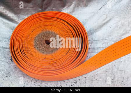 Strap for securing cargo lies on a blue - gray plastic bag in close-up. Stock Photo