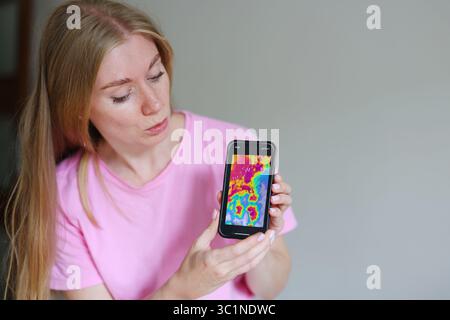 woman checking severe storm alert on phone, climate crisis, mobile forecast, danger warning Stock Photo