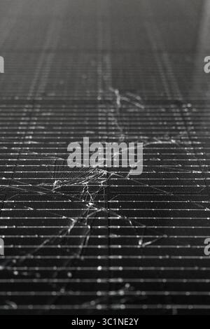 Close-up of a shattered photovoltaic solar panel displaying extensive surface damage Stock Photo