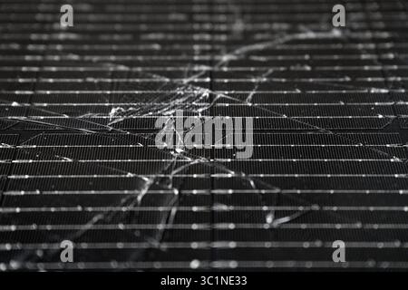 Close-up of a shattered photovoltaic solar panel displaying extensive surface damage Stock Photo