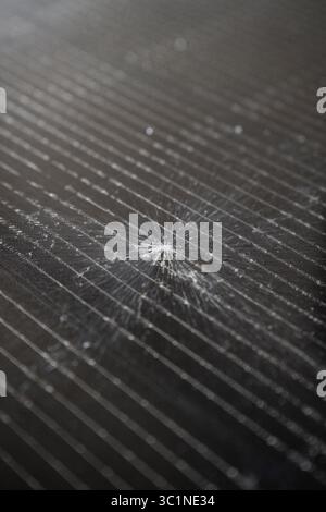 Close-up of a shattered photovoltaic solar panel displaying extensive surface damage Stock Photo