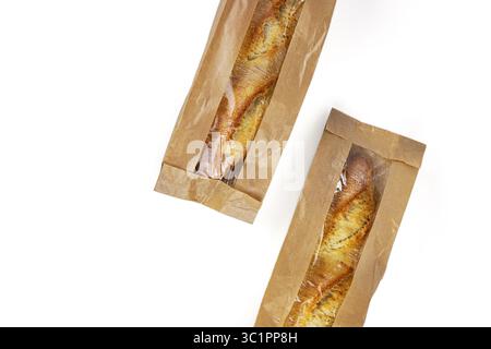 Two crusty golden baguettes packed in eco friendly brown kraft paper bags with transparent plastic windows, isolated on a white background.; Stock Photo
