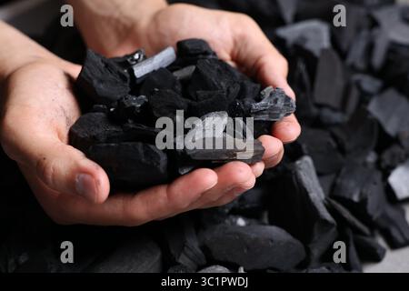 Man with black coals over pile, closeup Stock Photo
