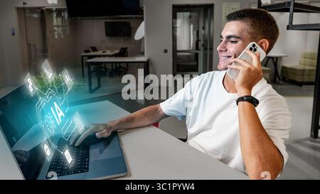 Young man engages with artificial intelligence technology while using laptop and smartphone in modern workspace Stock Photo
