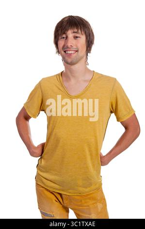 Young man stands happily with hands on hips, wearing a vibrant yellow shirt and jeans. Stock Photo