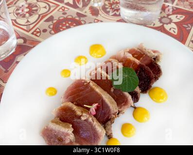 Tuna steak in a white plate on the table. Seafood. Healthy food. Directly above. Stock Photo