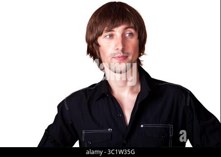 A young man stands confidently, showcasing a stylish look and relaxed demeanor. Stock Photo