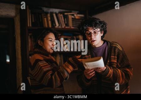 Two young adults discussing a book in a cozy library setting, engaging in a thoughtful conversation surrounded by bookshelves in a warm and Stock Photo