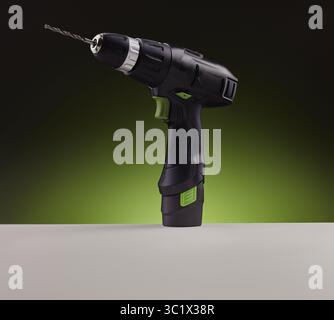 A black and green cordless drill is prominently displayed against a vibrant green and black gradient background. The drill features a comfortable grip Stock Photo