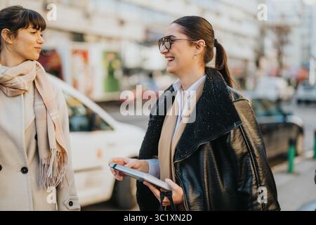 Two women engaging and smiling during an outdoor urban meeting Stock Photo