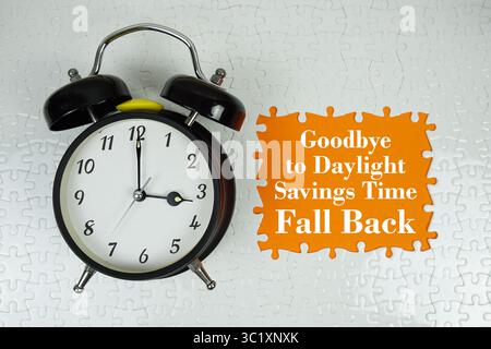 Goodbye to Daylight Savings Time Fall backtext with alarm clock on orange background Stock Photo