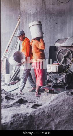 Construction workers collaborate in mixing cement, showcasing solid teamwork and efficiency in real on-site building operations. Stock Photo