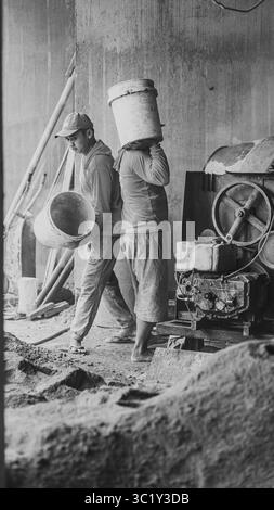 Construction workers collaborate in mixing cement, showcasing solid teamwork and efficiency in real on-site building operations. Stock Photo