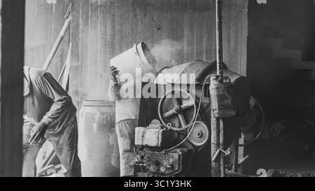 Construction workers collaborate in mixing cement, showcasing solid teamwork and efficiency in real on-site building operations. Stock Photo