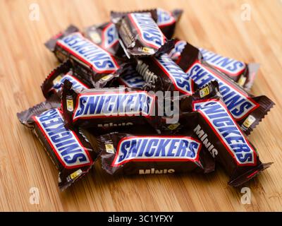 Tambov, Russian Federation - July 16, 2025 Heap of Snickers chocolate bars on a wooden background. Stock Photo
