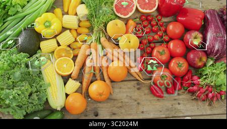 Displaying wooden tabletop featuring fresh lettuce, avocado, tomatoes, carrots and eco icons Stock Photo