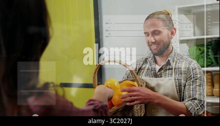 Handing store clerk wearing plaid shirt apron giving customer basket of oranges in produce section Stock Photo