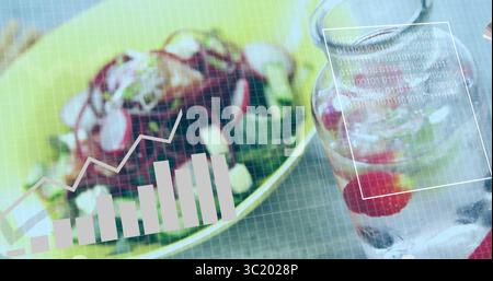 Displaying salad bowl with greens and cheese near infused water jar, under overlay charts and code Stock Photo